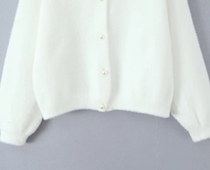 Détail du cardigan blanc duveteux avec boutons en perles élégants et texture très douce