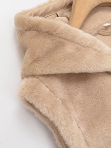 Gros plan sur la texture en fausse fourrure beige d'un gilet à capuche en polaire
