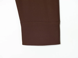 Gros plan du poignet de chemise marron foncé avec des finitions de couture soignées