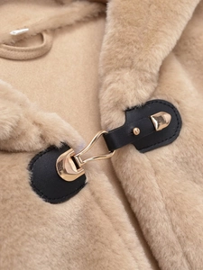 Gros plan du crochet doré sur un gilet à capuche en fausse fourrure beige doux