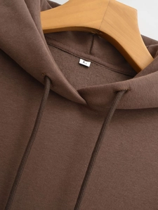 Detail of soft fleece lining and size L label inside a dark brown hoodie sweatshirt
