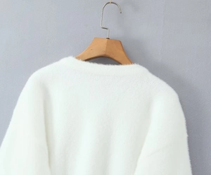 Gros plan d'un cardigan en peluche blanc doux avec col rond élégant et boutons de perles