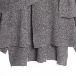 Détail d'un tricot gris foncé présentant un ourlet asymétrique et une texture de qualité