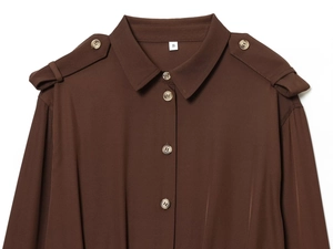 Détail du col de chemise marron avec pattes d'épaule et boutons aux tons ambrés