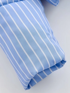 Close-up of light blue and white vertical striped fabric with twill texture and soft finish
