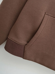 Close-up of brown hoodie showing high-quality fabric texture and ribbed hem detail