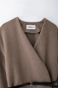 Detailed close-up of brown wool blend jacket featuring a v-neckline and black crocodile belt
