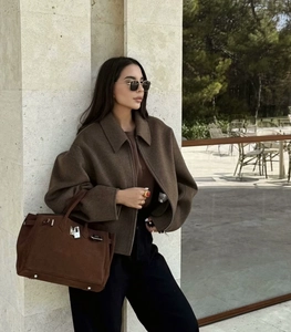 Detail of dark brown wool jacket zipper and premium suede handbag with metal lock hardware