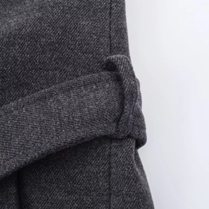Detailed macro view of charcoal grey wool fabric texture and matching waist belt loop