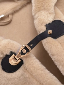 Gros plan détaillé du gilet en fausse fourrure camel avec brides en cuir noir et boucles dorées