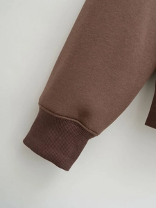 Close-up of ribbed cuffs and soft cotton fabric on a brown casual hoodie set