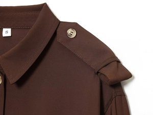 Détail d'une chemise plissée marron avec pattes d'épaule et boutons polis