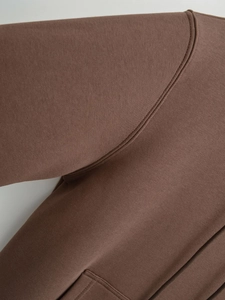 Detailed close-up showing reinforced seams and knit texture on the brown hoodie shoulder