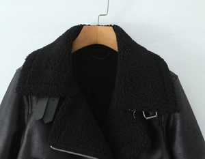 Detail of faux leather biker jacket featuring a black shearling lapel and metal zipper