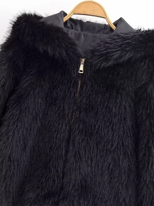 Detail of the high-quality black faux fur texture with a gold zipper and plush hood