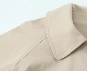 Macro shot of notch lapel and shoulder seams on this beige twill trench coat for women