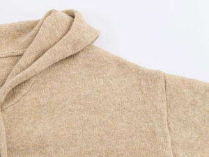 Detailed close-up of chunky knit texture and shoulder seam on a beige zip-up hoodie