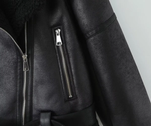 Detail of black shearling jacket showing leather texture and silver zipper hardware