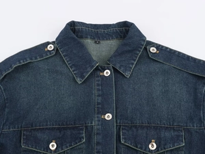 Detalle de chaqueta vaquera azul oscuro con cuello, charreteras y bolsillos frontales