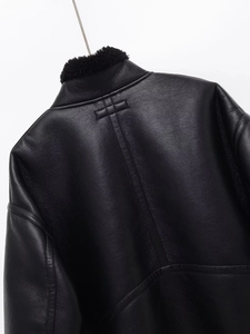 Detail of premium black leather jacket showing grainy texture and fleece collar seams