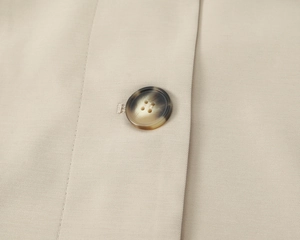 Close-up of a marble-textured button and twill fabric on a classic trench coat