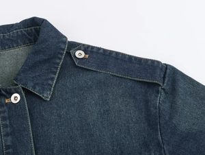 Detalle del hombro de una chaqueta vaquera azul oscuro con botones de bronce