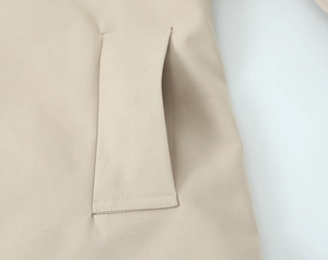 Close-up of side pocket detail on khaki twill trench coat with reinforced stitching