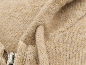 Detail of oatmeal knit fabric showing textured weave, hoodie drawstring, and silver zipper
