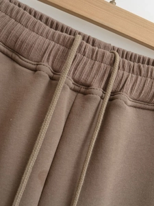 Detail of elastic ribbed waistband and woven drawstring on taupe jogger pants