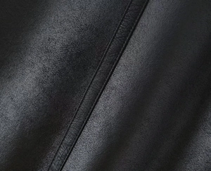 Close-up of premium black faux leather texture with fine stitching detail on jacket