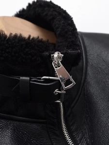 Detailed macro view of black faux leather jacket with thick shearling collar and metal buckle