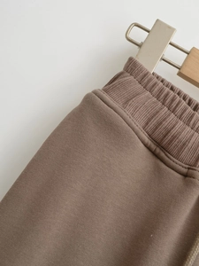 Detailed macro view of the elastic ribbed waistband on dark brown casual pants