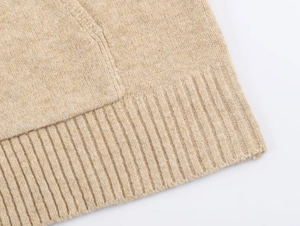 Detailed macro view of the oatmeal knit fabric texture and ribbed hem on this winter jacket