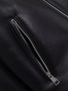 Detailed close-up of premium black leather jacket with silver zipper and lychee texture