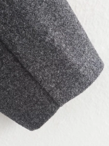 Close-up of deep gray wool blend fabric showing fine fiber texture and stitching