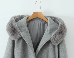 Detail of grey hooded wool coat featuring premium faux fur trim and textured fabric