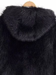 Close-up of fluffy black faux fur hood and back texture on a wooden hanger