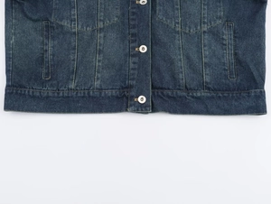 Vista de detalle del dobladillo de la chaqueta vaquera azul oscuro con botones de metal plata