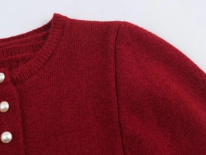 Detail of red knit cardigan featuring classic crew neck and elegant pearl buttons
