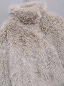 Close-up detail of high-density long-fiber faux fur texture on elegant beige winter coat