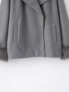 Detailed view of gray wool coat featuring luxurious faux fur cuffs and classic side pocket