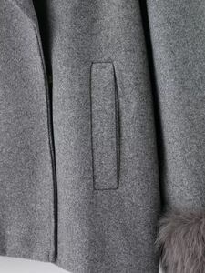 Close-up of grey wool coat featuring textured fabric and luxurious faux fur cuffs