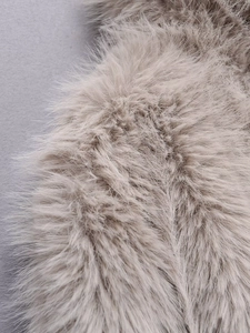 Macro shot of dense faux fur texture on long sleeve coat in beige brown shade