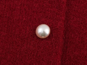 Macro shot of a white pearl button on thick red plush knit fabric for winter tops