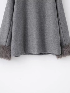 Detail of wool coat hem and sleeve featuring dark grey faux fur trim on grey fabric