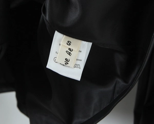Close-up of smooth black lining and dual care labels on the faux leather PU jacket