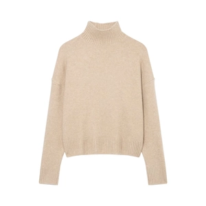 Detail of oatmeal turtleneck sweater showing ribbed cuffs and soft knit texture
