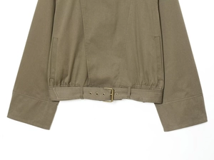 Dettaglio giacca in twill verde militare con cintura, fibbia in metallo e orlo elastico