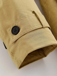 Detalle del puño de la chaqueta caqui con botón negro y correa ajustable de mezcla de algodón