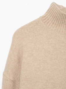 Detail shot of oatmeal knit sweater showing turtleneck collar and soft wool texture